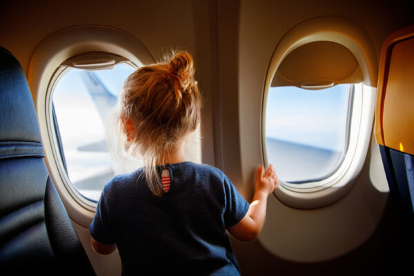 Little Girl Traveling on Airplane Securely with Family